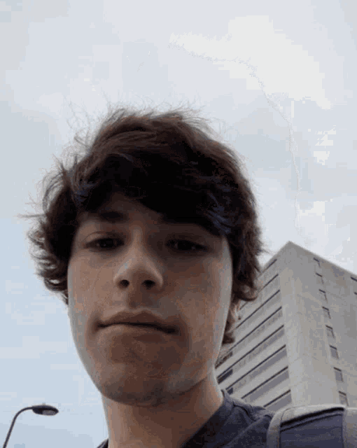 a young man with a backpack looks at the camera