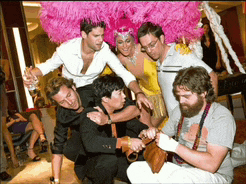 a woman in a pink feathered headpiece is surrounded by a group of people