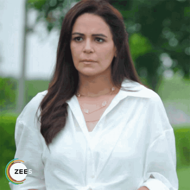 a woman wearing a white shirt and a necklace with the word zees on the bottom