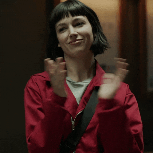 a woman in a red jacket is clapping her hands in the air