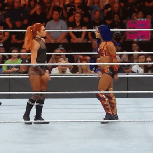 two women in a wrestling ring with a sign that says live wrestling