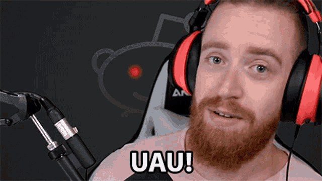 a man with a beard wearing headphones says uau in front of a microphone
