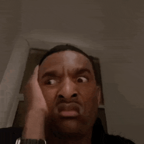 a close up of a man making a funny face with his hand on his forehead .