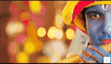 a man with blue paint on his face is wearing a yellow hat