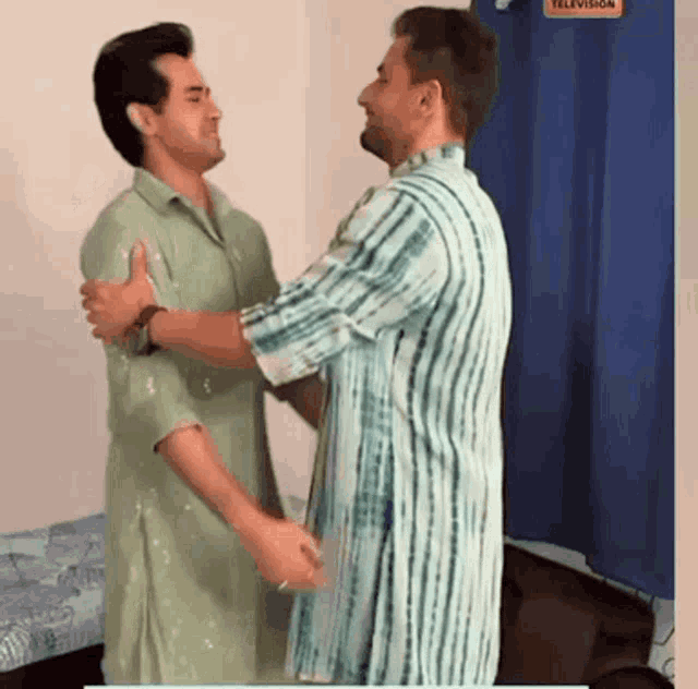 two men hugging each other in front of a television sign