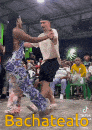 a man and a woman are dancing in front of a crowd that says bachatealo on the bottom