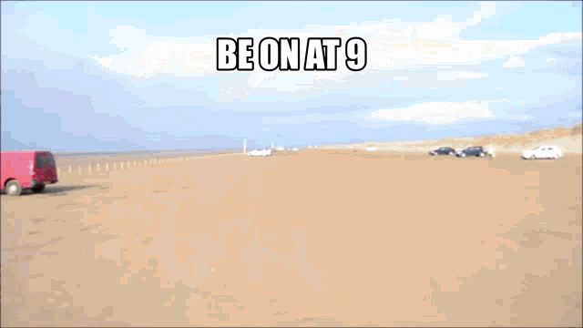 a red car is driving on a sandy beach and says be on at 9
