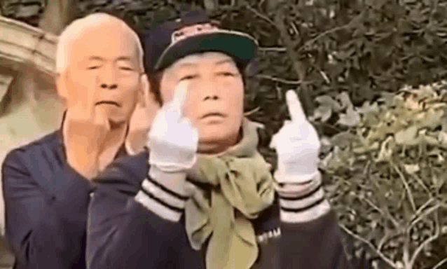 a man and a woman are standing next to each other making a middle finger sign .