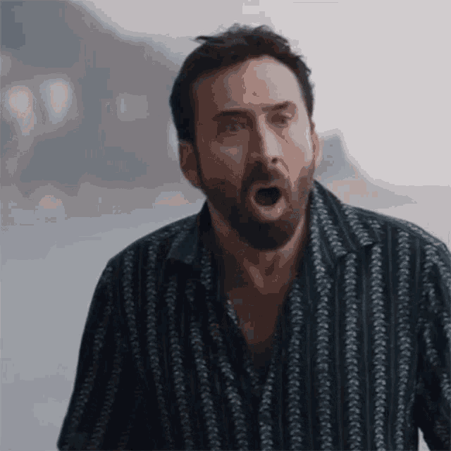 a man with a beard and a striped shirt is making a funny face .