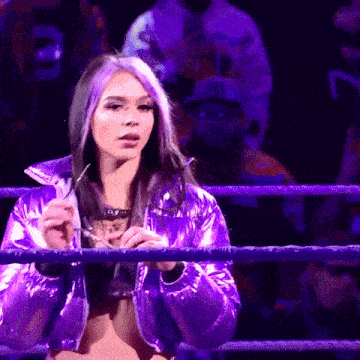 a woman in a purple jacket is standing in a ring
