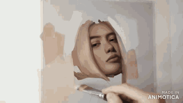 a person is painting a picture of a woman 's face with a brush .