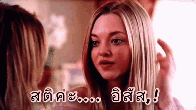 a woman with blonde hair is looking at another woman 's face with a caption in a foreign language .
