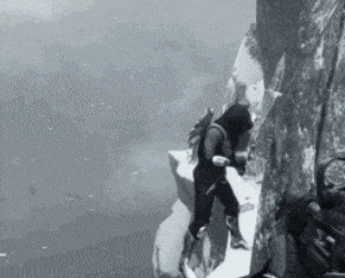 a black and white photo of a person standing on a cliff .