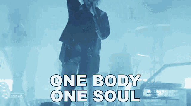 a man singing into a microphone with the words one body one soul written below him