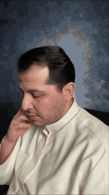 a man wearing a white shirt has his hand on his face