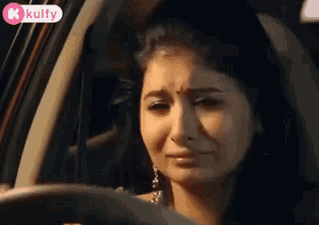 a woman is crying while driving a car and looking out the window .