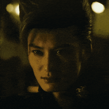 a close up of a man 's face with his hair in a ponytail
