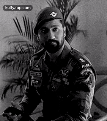 a black and white photo of a man in a military uniform and a beret .