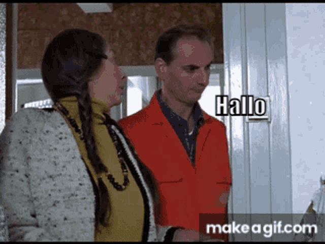 a man and a woman are standing in front of a sign that says hallo on it