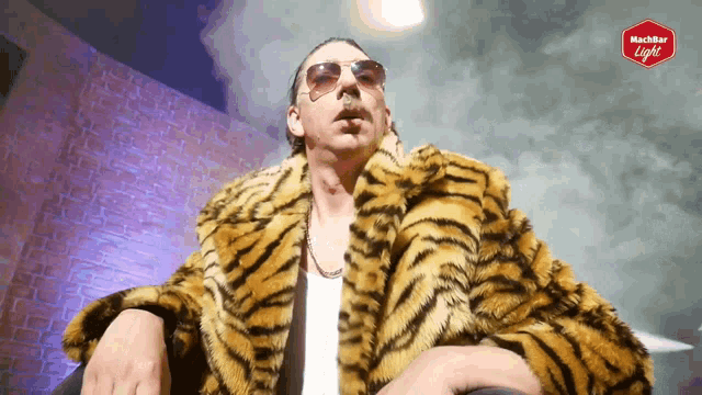 a man wearing a tiger fur coat and sunglasses is standing in front of a sign that says mischbar light