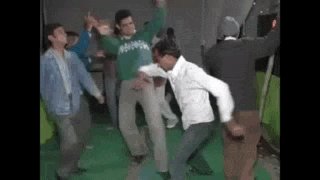 a group of men are dancing on a green floor .