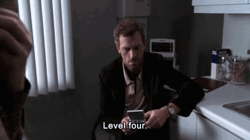 a man sitting on a counter looking at a cell phone with the words level four written above him