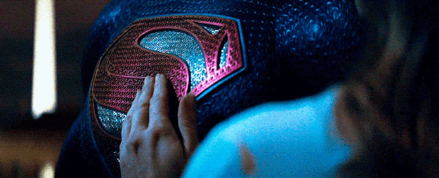 a close up of a person 's hand touching a superman logo
