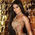 a woman with long black hair is standing in front of a gold wall .