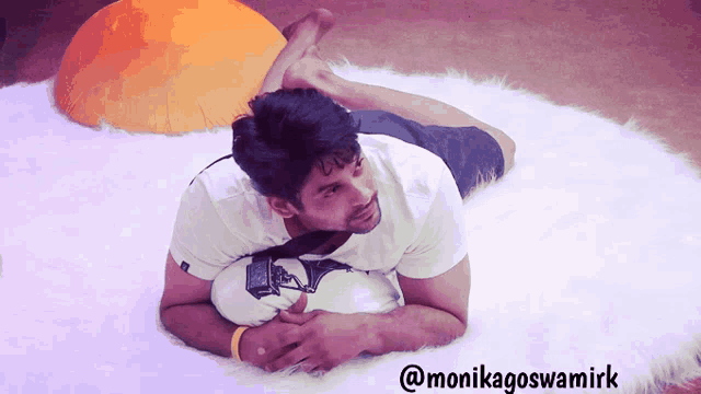 a man laying on his stomach with a soccer ball and the name monikagoswamirk on the bottom right
