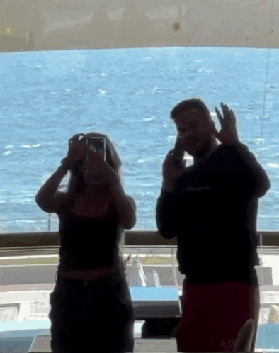 a man and a woman are taking a picture of a body of water