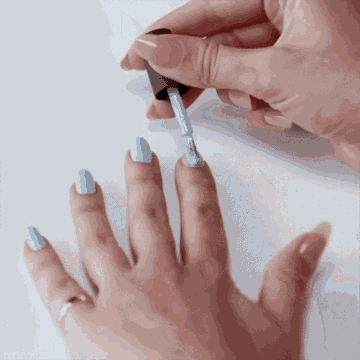 a woman is applying blue nail polish to her fingernails