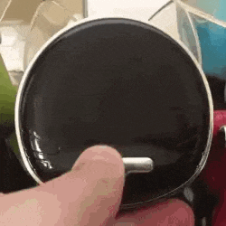 a close up of a person 's hand holding a black circle with a silver handle .