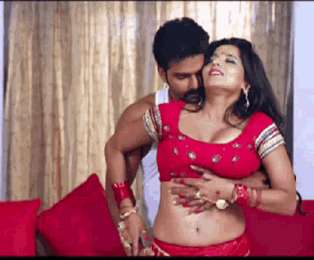 a man is touching a woman 's stomach while she is wearing a red blouse