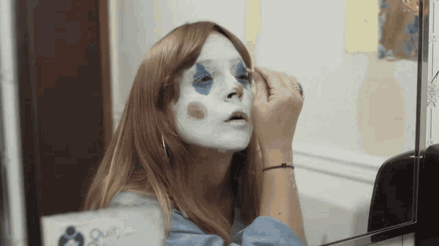 a woman with a clown makeup on her face looks at herself in the mirror