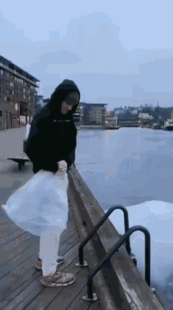 a person is standing on a dock holding a plastic bag
