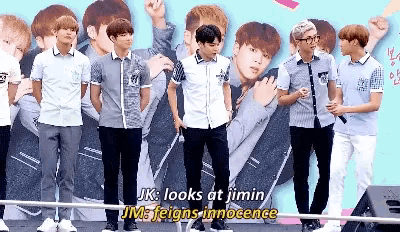 a group of young men standing next to each other with the words jk looks at jimin