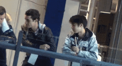 a group of young men are standing next to each other behind a fence .