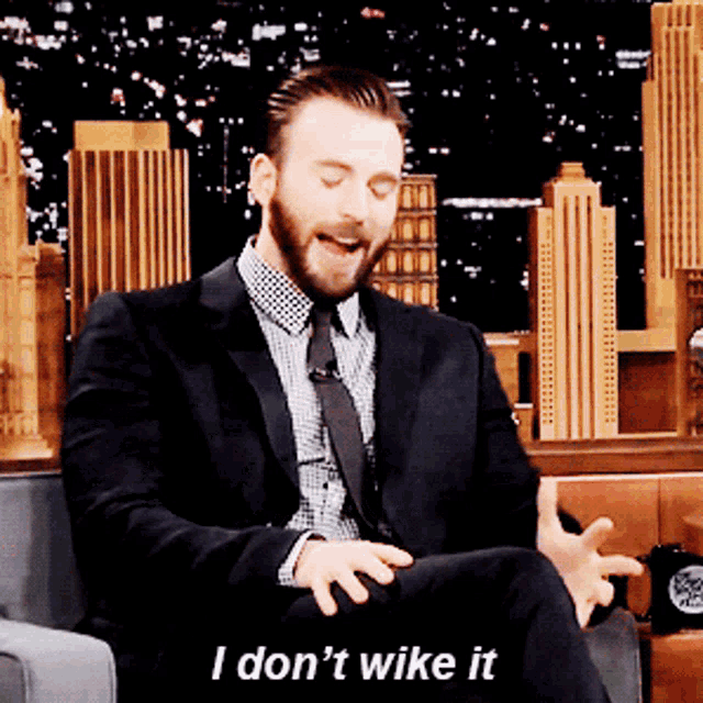 a man in a suit and tie is sitting in a chair and says " i don 't wike it "
