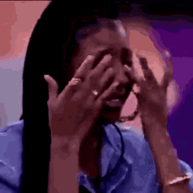 a woman is covering her face with her hands while crying