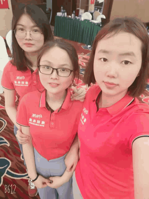a woman wearing a red shirt that says xiamen stands with two other women
