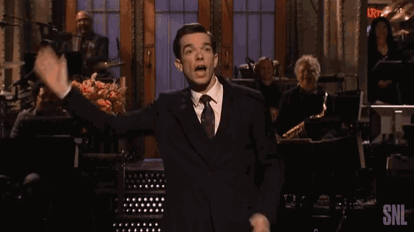 a man in a suit and tie is standing in front of a snl logo