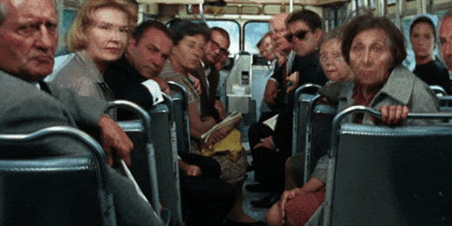 a group of people are sitting on a bus and one of them is holding a book