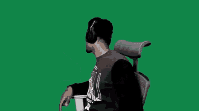 a man wearing headphones is sitting in an office chair on a green screen
