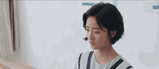 a young woman is sitting at a table looking at a piece of paper and a box .