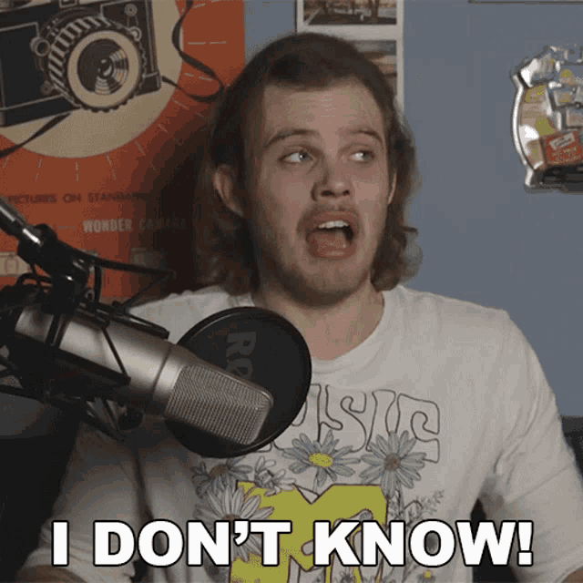 a man in front of a microphone with the words i don 't know on his shirt
