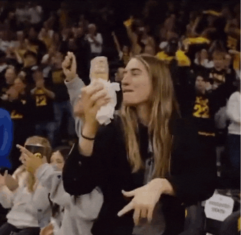 a woman is holding a tissue in her hand while sitting in the stands at a basketball game