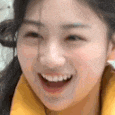 a close up of a woman 's face with her mouth open and a yellow jacket on .