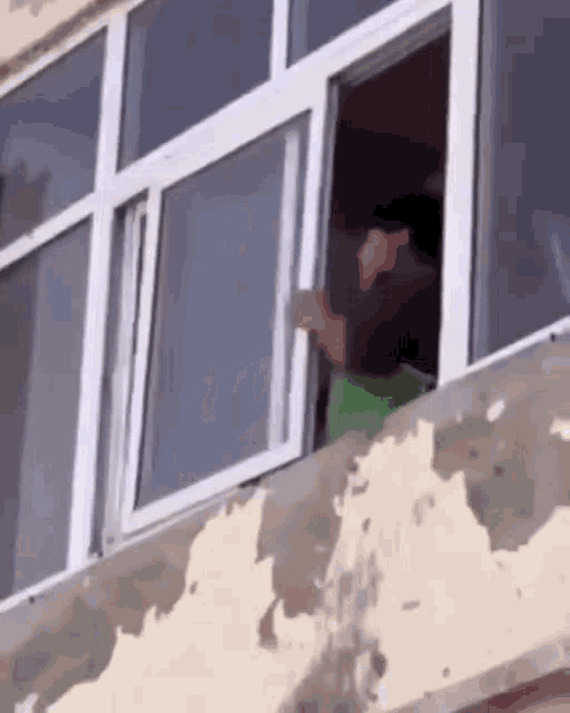 a person is standing on a balcony looking out a window .
