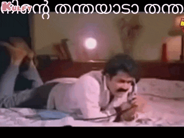 a man is laying on a bed talking on a telephone .