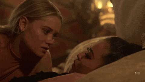 two women are kissing on a bed .